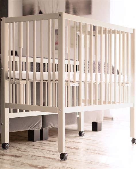 Otroška posteljica s spuščeno stranico ob starševski postelji