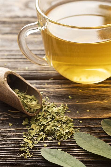 Ženska, ki doji otroka, s skodelico zelenega čaja ob sebi