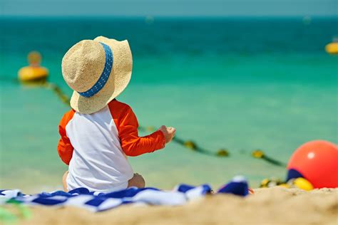 Otrok na plaži s sončno kapo