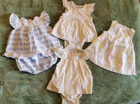 Dojenček oblečen v lahke bombažne pajace v prijetno osvetljenem prostoru