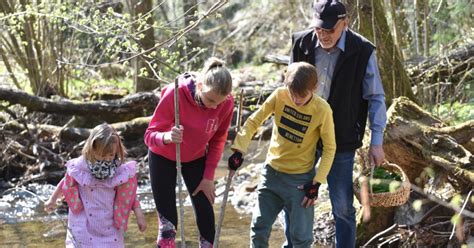 družina objema nosečnico v naravi