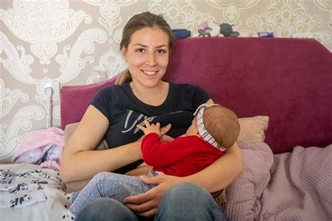 Ženska, ki se spočiti in nasmejana drži svojega dojenčka