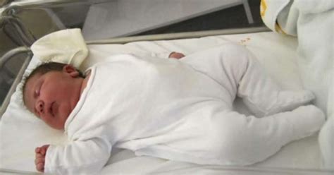 Dojenček leži v naročju s podporo za glavo in hrbet.