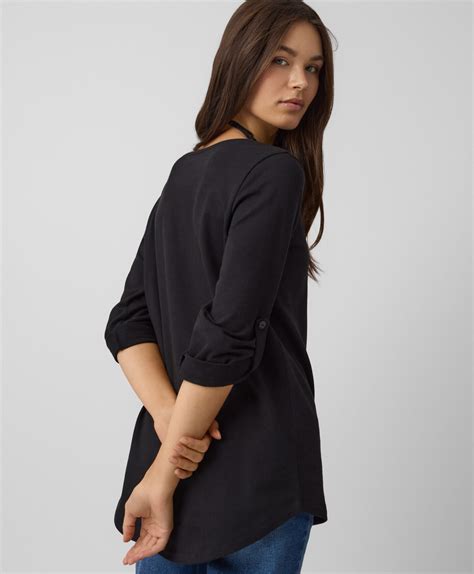 Ženska z zaobljenim trebuhom, ki si nežno masira stegno.