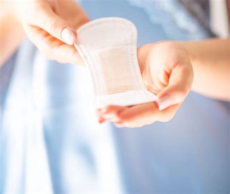 Nosečnica z zaskrbljenim obrazom gleda na higienski vložek z rahlim krvavim madežem.