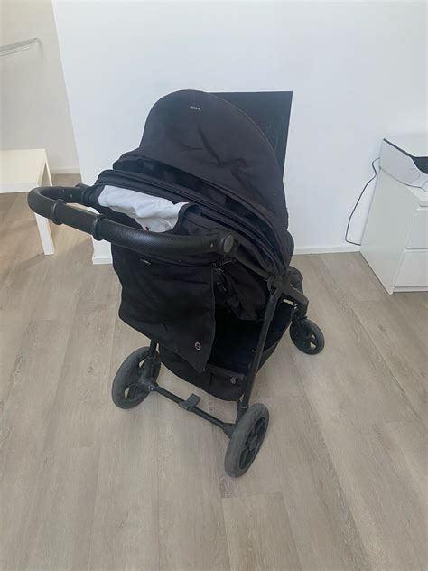 Ženska, ki nosi zložen voziček marela kot torbo na rami