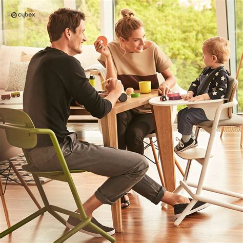 Dojenček, ki sedi na visoki stolček in ga starš hrani z žličko.