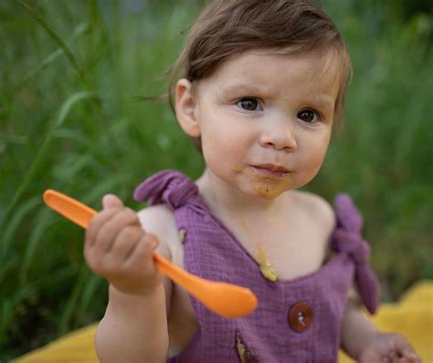 Dojenček, ki je pripravljen na gosto hrano, ob družinskem obroku.