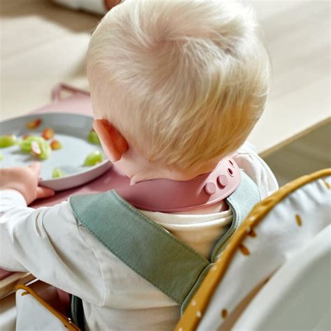 Dojenček v visokem stolu, ki se uči jesti sam