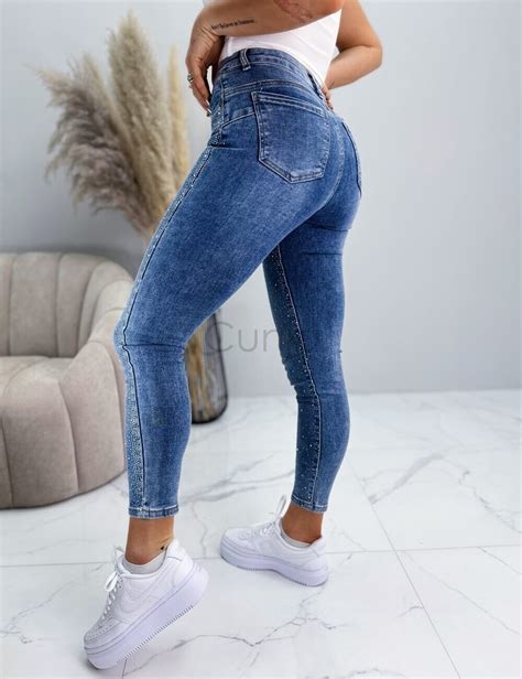 Nosečnica v tretjem trimesečju, ki nosi udobne traper hlače z visokim pasom.