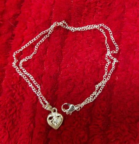 Detail srebrne verižice z obeskom nogice