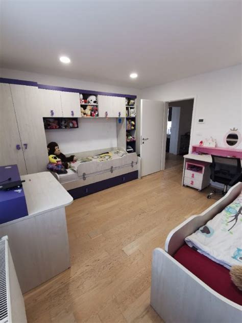 Ilustracija otroške sobe, ki prikazuje različne kotičke za igro, branje in ustvarjanje.