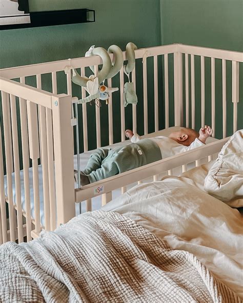 Novorojenček spi v zibelki ob postelji staršev