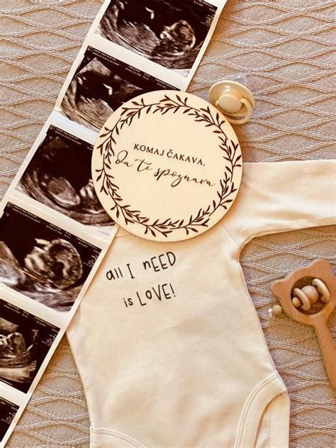 Nosečnica in partner držita milestone kartico z napisom 