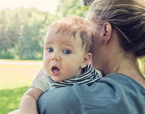 Dojenček, ki ga drži mama v pokončnem položaju med hranjenjem