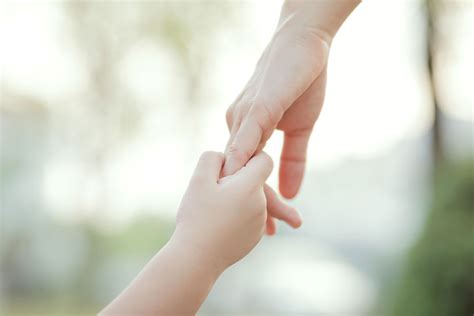 Ženska roka, ki drži otroško roko.