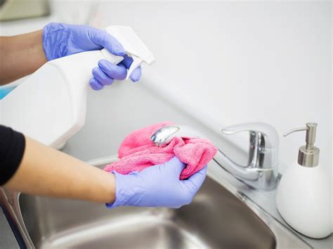 Nosečnica v kopalnici, ki se ob čiščenju umivalnika drži za korito zaradi ravnotežja