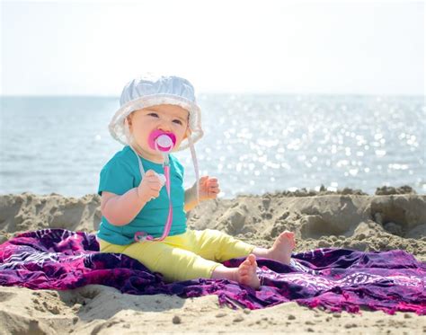 Nosečnica z otrokom na plaži z uporabo zaščitne kreme