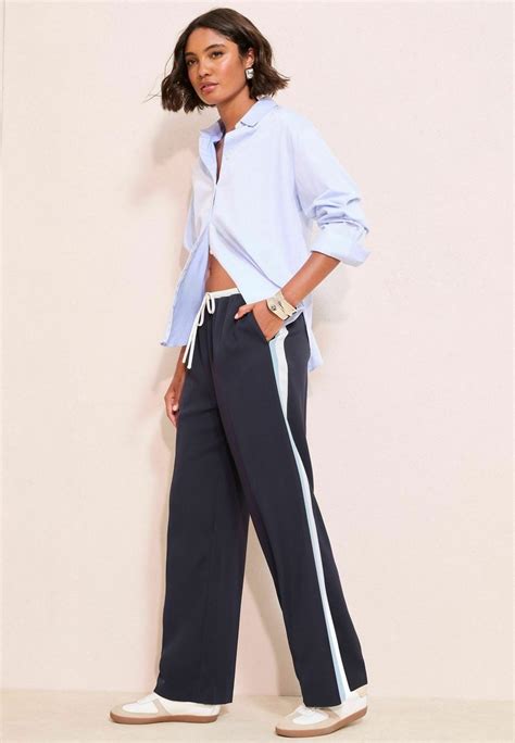 Ženska v širokih hlačah in črtasti srajci