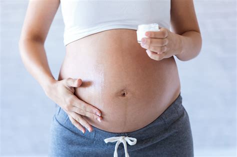 Ženska si nanaša kremo proti strijam na trebuh