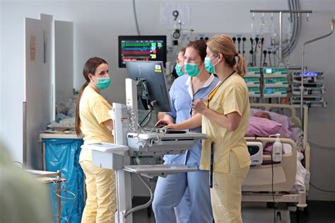 Ženska, ki vstaja iz postelje ob pomoči medicinske sestre