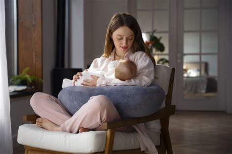 Mlada mama doji otroka na blazini Ergobaby