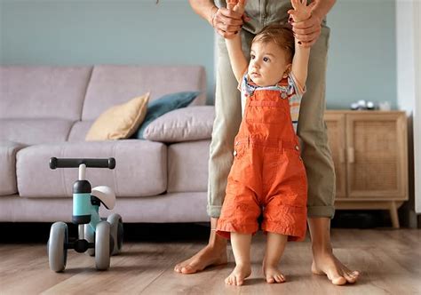 Dojenček, ki se drži pohištva in poskuša hoditi